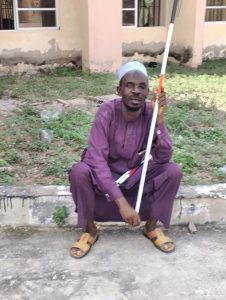Visually impaired person sitting with white cane